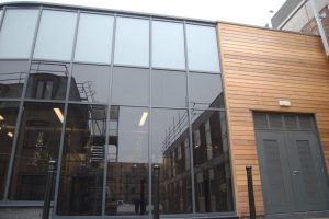 Outside a wooden clad building with large windows
