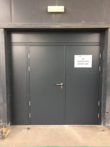 Black security door with black panels and a sign