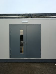 Grey security door with panel on a white building