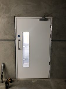 White security door with a window in a grey wall