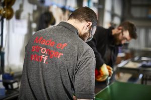 Man wearing a grey shirt with the text saying "made of stronger stuff"