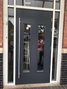 Black security door with windows and a tall push handle