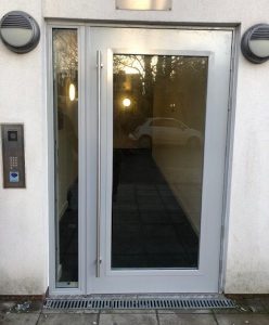 Grey door with a large window and a keypad to the left