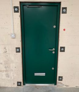 Green security door with a silver letterbox at the bottom