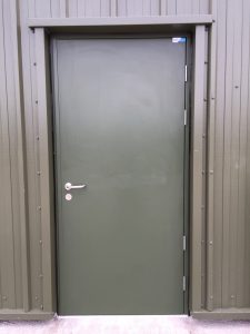Green security door outside a brown metal building