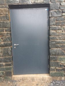 Black security door outside a black brick building
