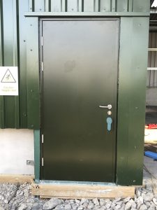 Black steel door on a green frame