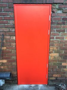 Red security door on an old brick wall