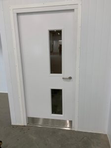 White security door in a white room with a black floor