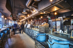 Inside of a restaurant or bar with exposed piping above and a brickwork finish