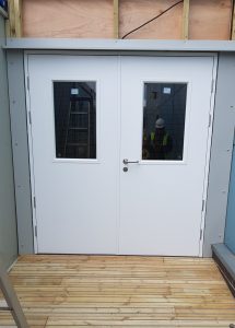 White double doors with window panels with unfinished wooden walls surrounding