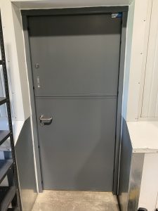 Grey security door in two separate panels in a white room