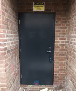 Black steel door surrounded by new bricks with a sign above