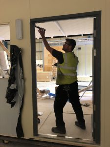 Man in a room with construction equipment working on a door frame