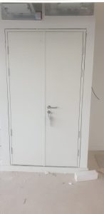 White double doors in a white room with a sliver handle