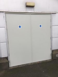 Cream Double security door with stickers on surrounded by white panelling