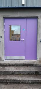 Purple security door with matching panel outside a grey building