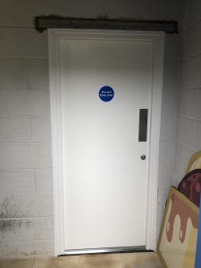 White fire exit door in a grey brick room