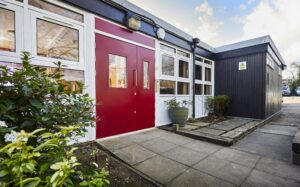 Red steel doors with a path leading up to it around a black and white building