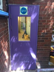 Blue fire exit door with a window looking into a building