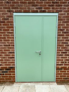 Green Steel Security Door surrounded by red brick