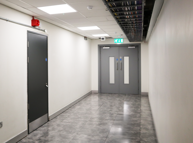 Internal fire rated double steel doorset in data centre with two vision panels at the end of a hallway