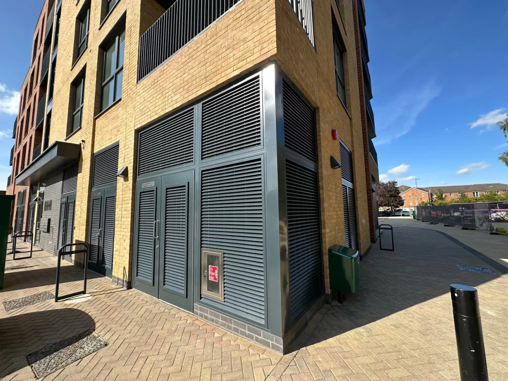 Double steel louvred doorset on the corner of a building with large louvred side and over panels