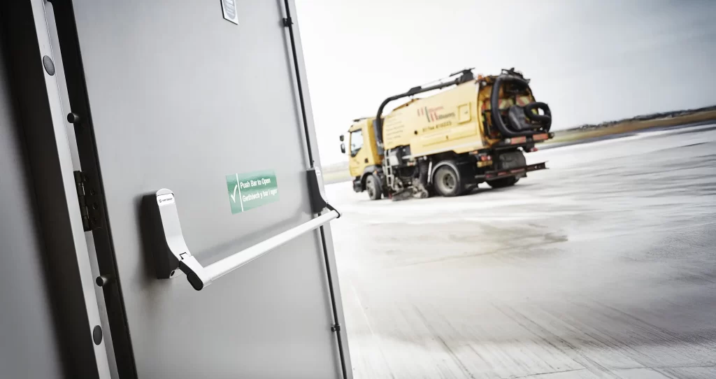 Panic and Emergency Exit devices - A Metador SafeguardX steel doorset opening outwards onto an industrial facility, featuring a BS EN 1125 panic exit push bar