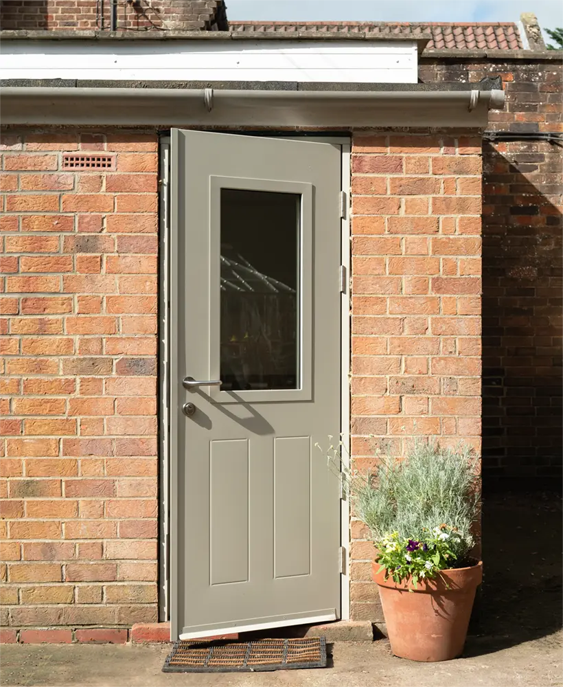 PAS 24 steel doorset opened slightly on the exterior of a residential out-building.